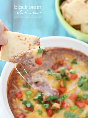 Pita chip is dipped into a cheesy Healthy Black Bean Dip + 43 Healthy Snack Ideas!