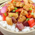 The most incredible Orange Chicken Stir Fry in a white bowl with chopsticks.