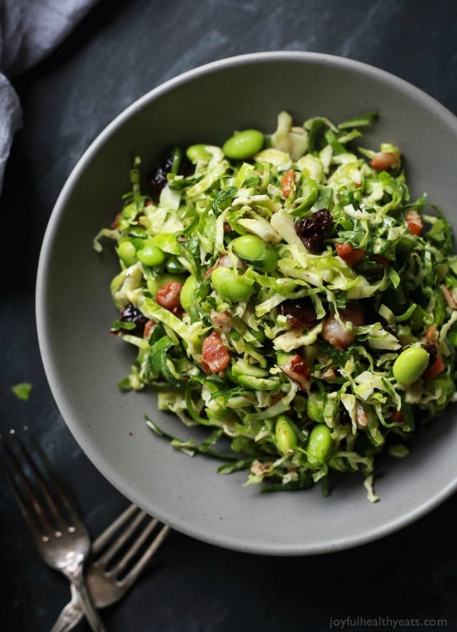 A light Autumn Kale & Shaved Brussel Sprout Salad infused with crispy bacon, edamame, and a surprise sweet fruit that compliments the dish perfectly.