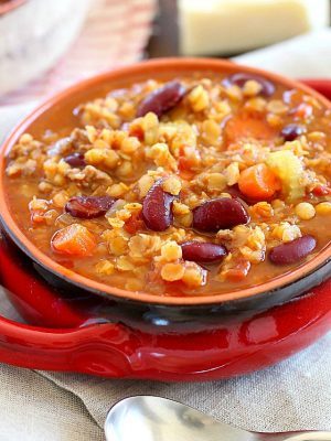 An incredible Sausage Lentil Chili in a red bowl with a spoon in front of it.