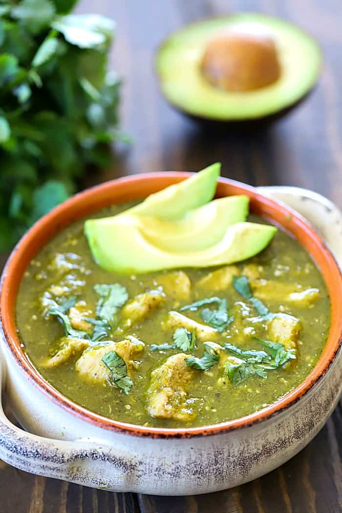 Pork Chili Verde soup in a white bowl with an avocado topping