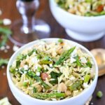 Top view of a beautiful Spring Orzo Salad filled with orzo, asparagus, toasted almonds, arugula, feta cheese and peas with a vinaigrette.