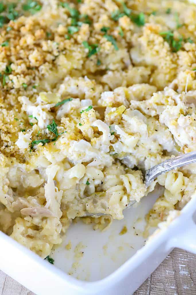 Giant scoop taken out of the side of the dish to show how creamy and delicious the rotini pasta, chicken and cream sauce look.