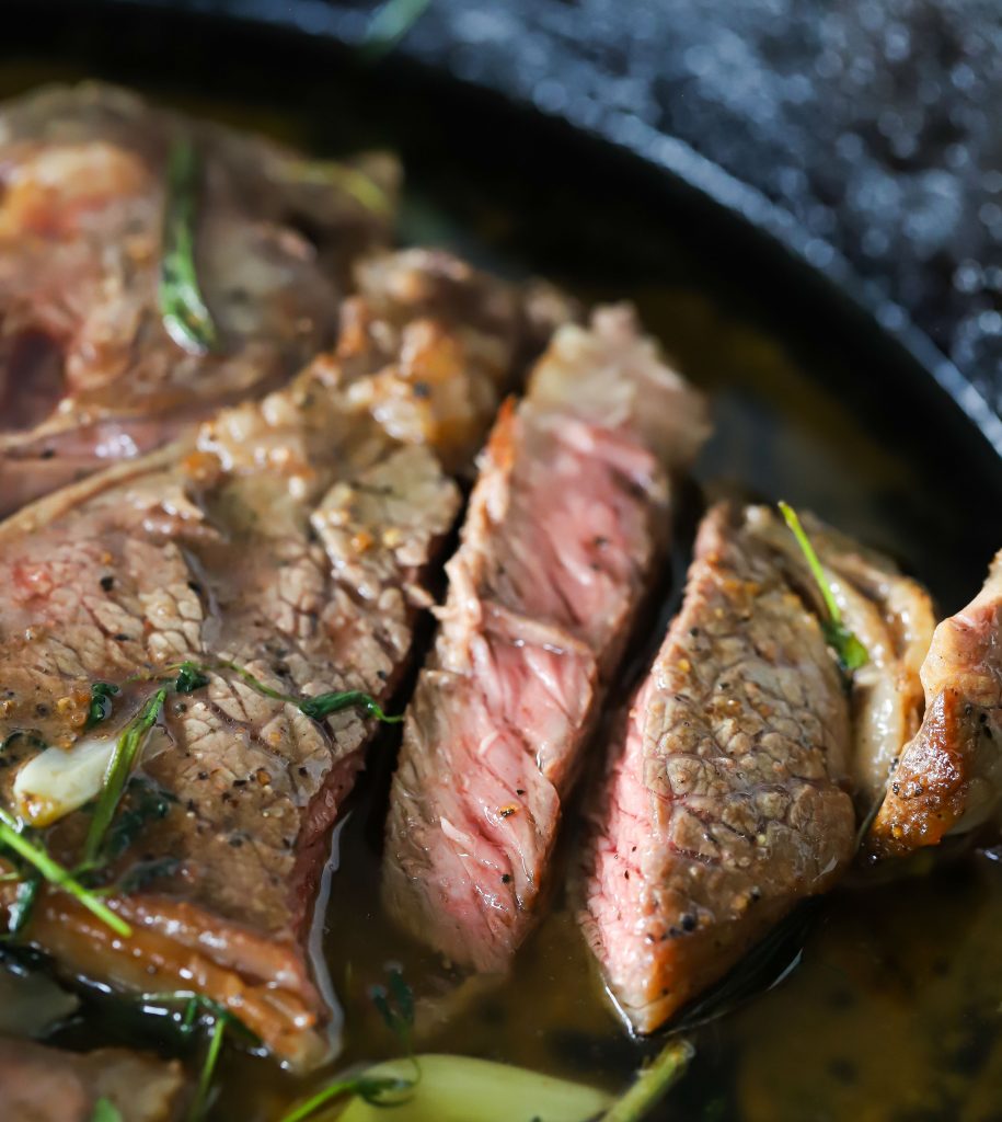 Sliced medium-rare ribeye in skillet